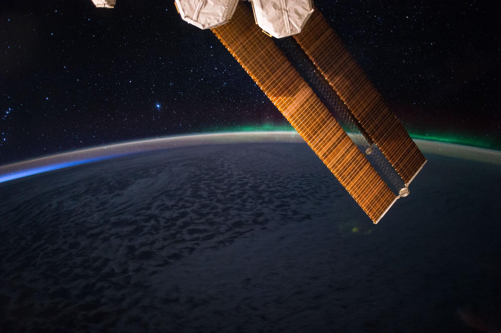 Space station solar arrays above Earth at night